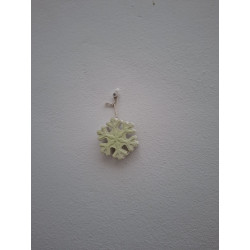 Adorno de copo de nieve clásico de cemento fosforescente con brazos ramificados colgado de forma vertical en pared exterior.