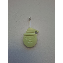 Adorno Papá Noel de cemento fosforescente con gorro navideño colgado de forma vertical en una pared blanca exterior.