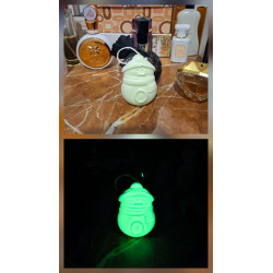Adorno Papá Noel de cemento fosforescente modelo redondeado mostrando su brillo verde y su silueta de día sobre mármol.