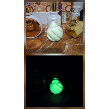 Adorno bola Navidad de cemento fosforescente con líneas diagonales mostrando su diseño de día y su brillo verde en la oscuridad.