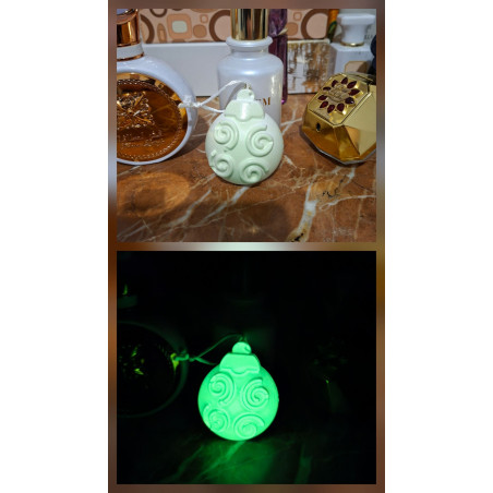 Adorno bola Navidad de cemento fosforescente con relieve de espirales mostrando su diseño de día y brillo verde en la oscuridad.