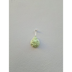 Adorno bola Navidad de cemento fosforescente con relieve de espirales colgado de forma vertical en una pared blanca exterior.