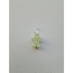 Adorno muñeco jengibre de cemento fosforescente con relieves decorativos colgado de forma vertical en una pared blanca exterior.