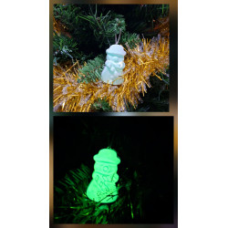 Adorno muñeco nieve de cemento fosforescente modelo bombín de día en el abeto y brillando verde de noche.