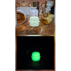 Adorno regalo de Navidad de cemento fosforescente mostrando su diseño con lazo de día y su brillo verde en la oscuridad.