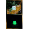 Adorno regalo de Navidad de cemento fosforescente con lazo de día en el abeto y brillando verde de noche.