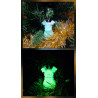 Adorno reno navideño de cuerpo entero de cemento fosforescente de día en el abeto y brillando verde de noche.