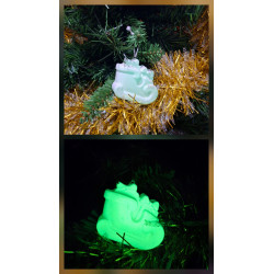 Adorno trineo Navidad de cemento fosforescente con regalos de día en el abeto y brillando verde de noche.