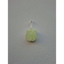 Adorno de tulipán de cemento fosforescente con silueta de pétalos colgado de forma vertical en una pared blanca exterior.