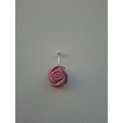 Adorno de rosa de cemento pintada a mano en color rosa colgado de forma vertical en una pared blanca exterior.