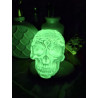 Adorno calavera de cemento fosforescente con corona de espinas mostrando intenso brillo verde en la oscuridad sobre el tocador.