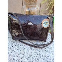 Bolso cruzado de cuero acharolado oscuro con relieve de escamas brillantes y correa ajustable fabricado en España.