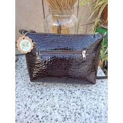 Vista trasera de un bolso cruzado de piel acharolada marrón con bolsillo exterior horizontal con cremallera.