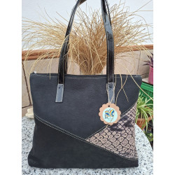 Vista de frente del bolso de hombro tipo tote en piel negra lisa de ante, con panel inferior asimétrico grabado efecto pitón.