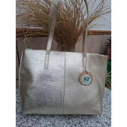 Vista frente bolso hombro tipo tote piel auténtica metalizada color dorado textura granulada costura central unión artesanal.