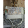 Vista frontal de bolso de piel de autor Lisviv con bloques en blanco, gris y panel central grabado de serpiente irisada.