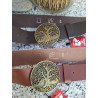Primer plano de hebilla circular calada con el motivo del árbol de la vida en relieve bronce sobre cinturón Lisviv.